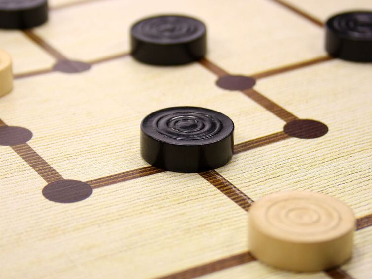 schwarze und weiße Mühlesteine auf einem Spielbrett