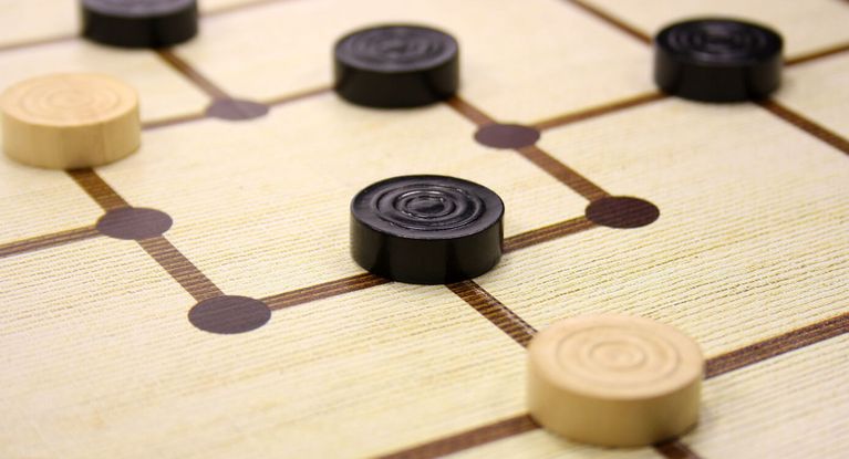 schwarze und weiße Mühlesteine auf einem Spielbrett