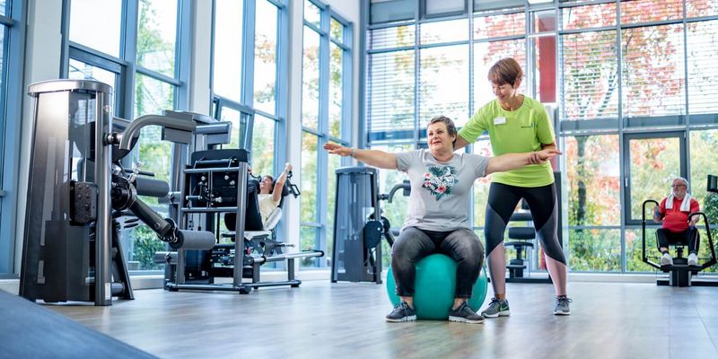 Therapeutin unterstützt Patientin in der Sporttherapie