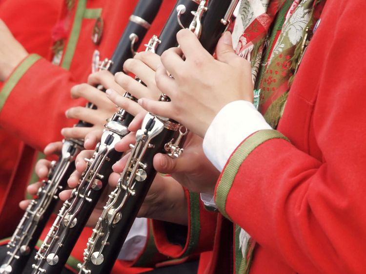 Musiker in roten Uniformen spielen Klarinette