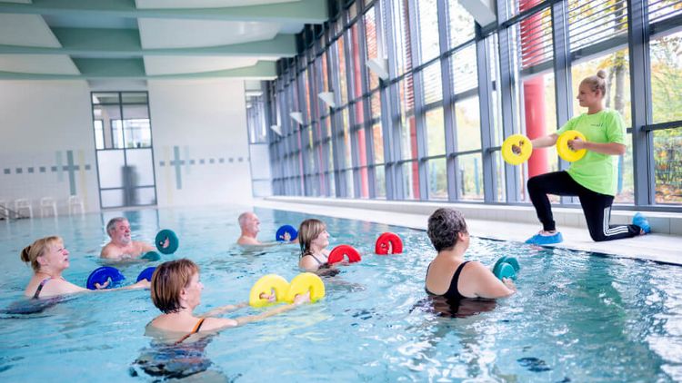 Therapeutin motiviert Patienten bei der Wassergymnastik