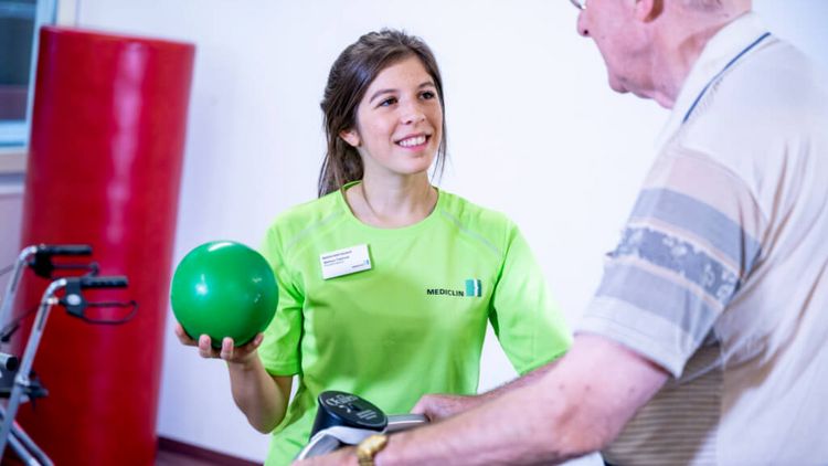 Älterer Patient trainiert in der Physiotherapie mit kleinen Bällen