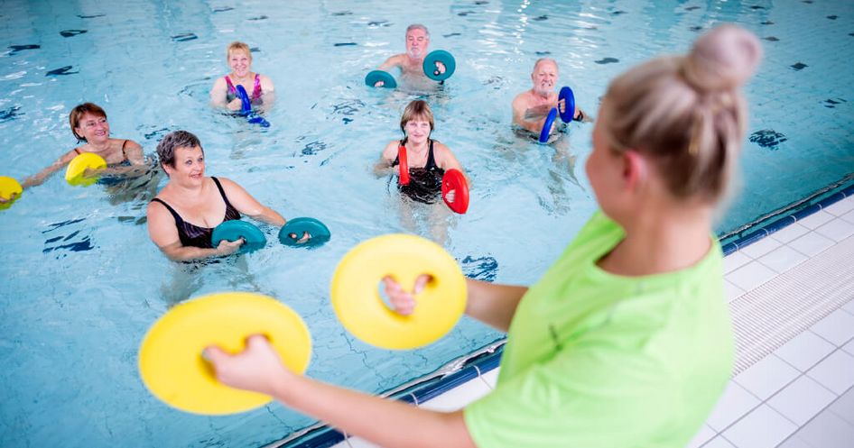 Therapeutin motiviert Patienten bei der Wassergymnastik