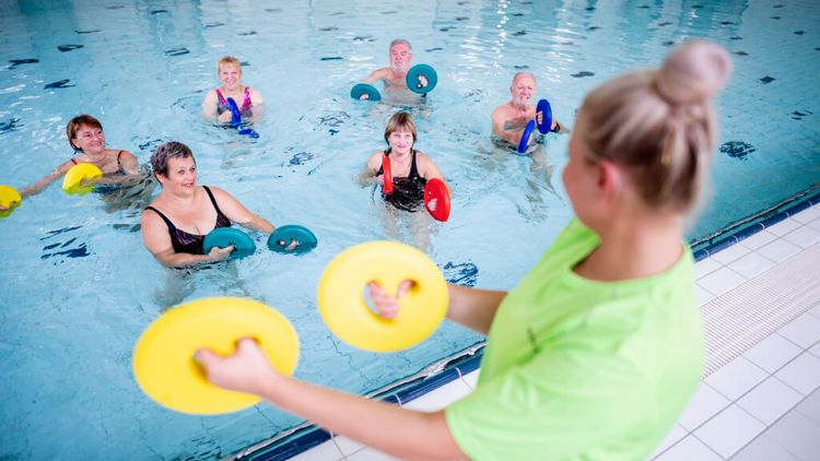 Therapeutin motiviert Patienten bei der Wassergymnastik
