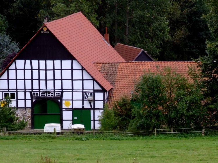 Fachwerkhaus mit rotem Dach in grünen Feldern